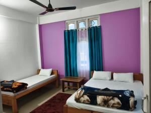 a bedroom with two beds and a purple wall at Valley View Homestay Sangti in Dirang Dzong