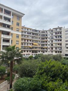 a large apartment building with a palm tree in the foreground at Studio Calif, face tram proche Mer in Nice