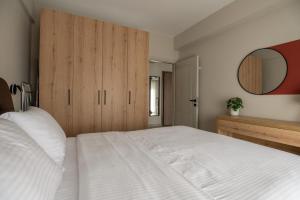 a bedroom with a white bed and a wooden cabinet at Likehome Apartments in Orestiada