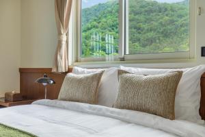 a bed with white sheets and pillows in front of a window at ItaThao Vacation Inn with Elevator in Yuchi