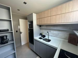 a small kitchen with a sink and a microwave at Apartamento moderno com 2 quartos e cama queen-size in Caruaru