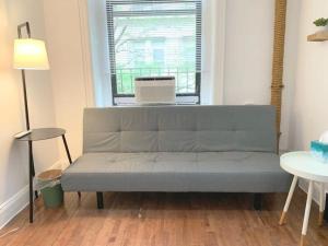 a couch in a living room with a window at Private room with Shared bath on Union Square 11 in New York