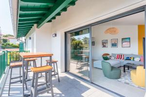 a patio with a table and chairs and a couch at Bel appartement avec terrasse vue rhune, parking et proche des plages de Bidart in Bidart