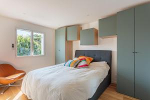 a bedroom with a large bed and a chair at Bel appartement avec terrasse vue rhune, parking et proche des plages de Bidart in Bidart