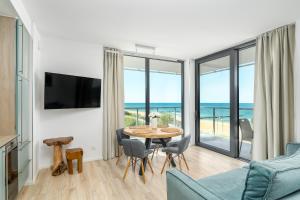 a living room with a table and a view of the ocean at Apartamenty JANTARIS Prestige by BALTIC CLUB in Mielno