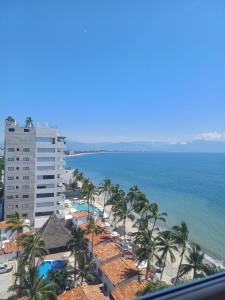 a view of a beach with palm trees and a building at Cozy Beachfront PH Getaway in Bucerías