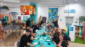 a group of people sitting at a long table at Medano Nest Hostel in El Médano