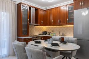 a kitchen with a table and chairs and a refrigerator at Mnēmes Apartment in Neoi Epivates
