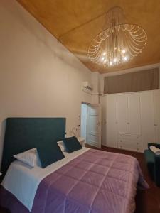 une chambre avec un grand lit et un lustre dans l'établissement Corte Pini Deluxe Apartment in historic center of Lucca, à Lucques