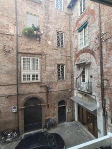 un vieux bâtiment en briques avec une cour devant dans l'établissement Corte Pini Deluxe Apartment in historic center of Lucca, à Lucques