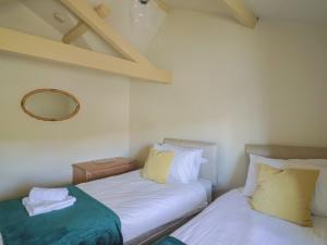 2 camas en una habitación pequeña con espejo en Drake's Hideaway, en Lyme Regis