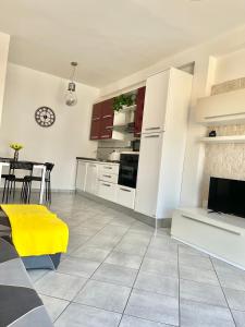 una cucina con mobili bianchi e un tavolo con una panca gialla di Casa Alice a Nizza Monferrato