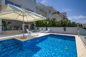 a pool with an umbrella and chairs and a table with an umbrella at Olymp Luxury Family House in Paphos
