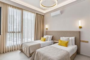 two beds in a hotel room with yellow pillows at Olymp Luxury Family House in Paphos +82 photos