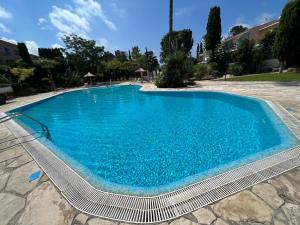 a large swimming pool with blue water at Natalia's 1 Bedroom Apartemnt in Paphos