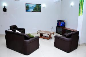 a living room with two chairs and a tv at Anuradha Holiday Apartments in Anuradhapura