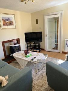 Una sala de estar con televisión y una mesa de café. en Croft cabin, en Fort William 14 fotos más