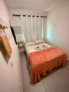 ein kleines Schlafzimmer mit einem Bett mit einer orangefarbenen Decke in der Unterkunft Peroba Ville Residence AP completo in Maragogi + 31 Fotos