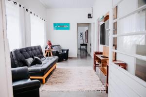 ein Wohnzimmer mit einer schwarzen Couch und einem Tisch in der Unterkunft Casa c/ Piscina e Área Gourmet Perto da Praia in São Sebastião