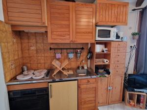 Elle comprend une petite cuisine avec des placards en bois et un évier. dans l'établissement **Studio Montagne 2/3 pers - Pied des pistes, centre station** - FR-1-393-43, à Saint-Michel-de-Chaillol