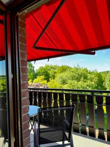 a red umbrella over a chair on a balcony at Möhne Ferienwohnung in Möhnesee