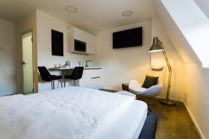 ein Schlafzimmer mit einem weißen Bett sowie einem Tisch und Stühlen in der Unterkunft Apartmenthaus Königsallee in Bayreuth