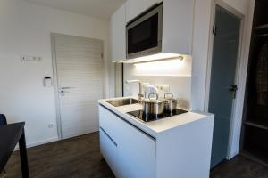 a white kitchen with a sink and a microwave at Apartmenthaus Königsallee in Bayreuth