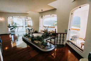 a living room with two large windows and plants at Conforto, Vista linda e Pé na Areia | Barequeçaba in São Sebastião