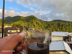 a hand holding a glass of beer with a mountain at Samara homestay in Mantaak