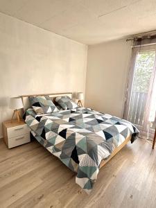 una camera da letto con un letto con una trapunta sopra di Appartement Biscarrosse - Centre-ville, terrasse, au calme - agréable, tout confort - 4pers a Biscarrosse