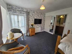 a room with a bed and a table and a television at The Ship Inn in Oundle