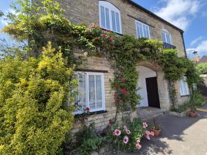 a brick house with a bunch of flowers on it at The Ship Inn in Oundle