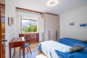 a bedroom with a bed and a desk and a window at Appartamento Valentina in Oggebbio