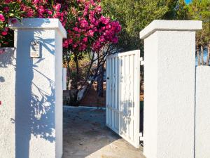 Una valla blanca con una puerta y flores rosas. en Villa Miriam - Klodge, en Olbia