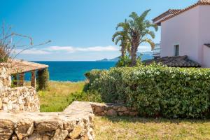 a house with a stone wall next to the ocean at Bellosguardo 3, 8 - Klodge in Olbia