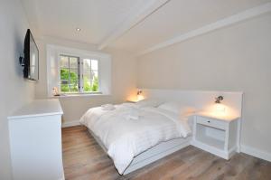 a white bedroom with a bed and a window at Doppelhaushälfte SPO-Stern in Böhl
