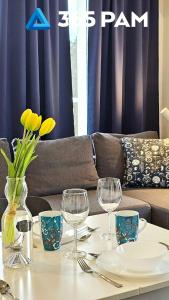 a table with wine glasses and a couch at 365PAM - Apartament Bliżej Morza w Gąskach in Gąski