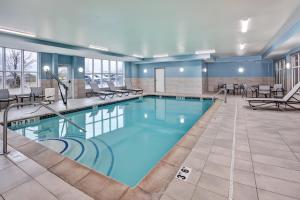 a pool in a hotel room with tables and chairs at Holiday Inn Express Hotel & Suites Auburn Hills by IHG in Auburn Hills