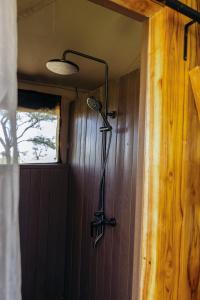 a shower in a room with a wooden wall at The African Kongoni Serengeti Camp in Nkunjila