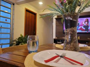 une table avec une assiette et un verre d'eau et un vase dans l'établissement Pousada Céu de Viracopos, à Campinas