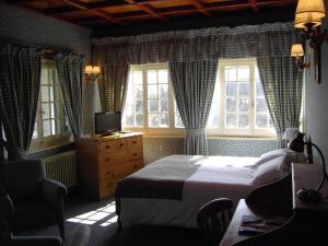 a bedroom with a bed and a chair and windows at Auberge Des Chasseurs in Échenevex