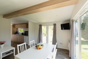 a kitchen and dining room with a white table and chairs at Naturcamping Lüneburger Heide - Chalets & Tiny Häuser in Soltau