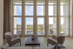 a living room with large windows and a couch and chairs at Mehr Meerblick - Stilvolle Ferienwohnung mit Panoramablick auf Ostsee und Saaler Bodden in Wustrow