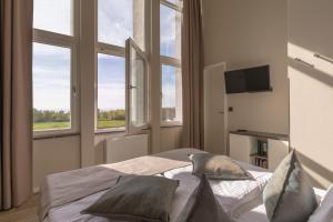 a bedroom with windows and a bed with pillows at Mehr Meerblick - Stilvolle Ferienwohnung mit Panoramablick auf Ostsee und Saaler Bodden in Wustrow