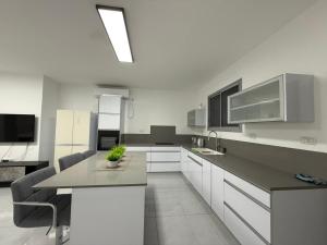 a kitchen with white cabinets and a table and chairs at בוטיק המשי in Bet Sheʼan