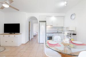 a white kitchen with a dining table and a television at Apartamento Palo Verde Golf in Islantilla