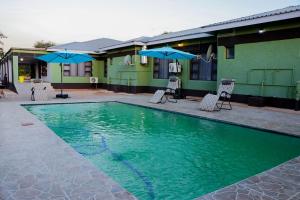a swimming pool with chairs and umbrellas next to a building at Amariah Lodge in Kasane