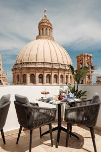 a table and chairs on a balcony with a building at 1926 La Galerie Boutique Art Suites in Valletta