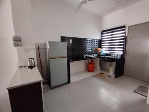 a kitchen with a refrigerator and a sink in it at Lilly Grove Homestay in Kampong Ayer Melintas Besar