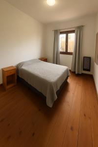 una camera con letto, finestra e pavimenti in legno di Casa Azucena a El Bolsón